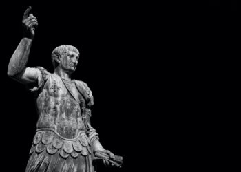 Estatua de Trajano en armadura militar romana con puño levantado. El emperador conquistador (98-117 d.C.) representado en pose de poder y mando, símbolo de su expansión territorial y dominio militar del Imperio.