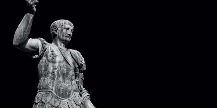 Estatua de Trajano en armadura militar romana con puño levantado. El emperador conquistador (98-117 d.C.) representado en pose de poder y mando, símbolo de su expansión territorial y dominio militar del Imperio.