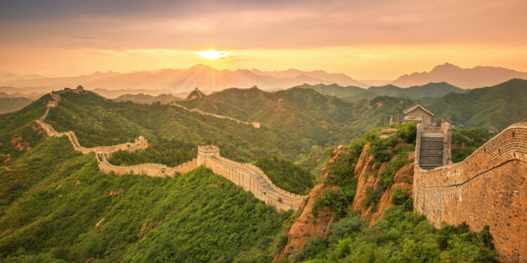 Gran Muralla China con múltiples torres de vigilancia Ming serpenteando entre montañas Beijing al atardecer.