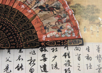 Caligrafía china antigua en abanico tradicional, representando la importancia del arte de la escritura en la civilización china.