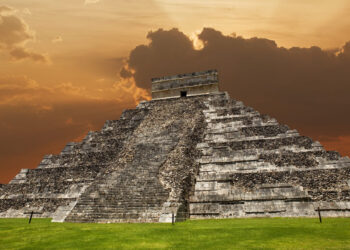 El Castillo de Chichén Itzá, pirámide maya de 24 metros de altura que muestra la fusión de estilos arquitectónicos maya y tolteca, con cielo dramático de atardecer en Yucatán, México