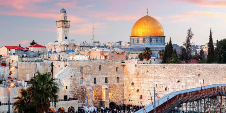 Vista de Jerusalén al atardecer con el Muro de las Lamentaciones en primer plano y el Domo de la Roca al fondo, los lugares más sagrados del judaísmo y el islam en la ciudad santa de las tres religiones abrahámicas