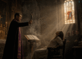 Sacerdote católico realizando un exorcismo en el catolicismo en una iglesia antigua, con crucifijo, libro litúrgico, incienso y luz dramática de vitrales.